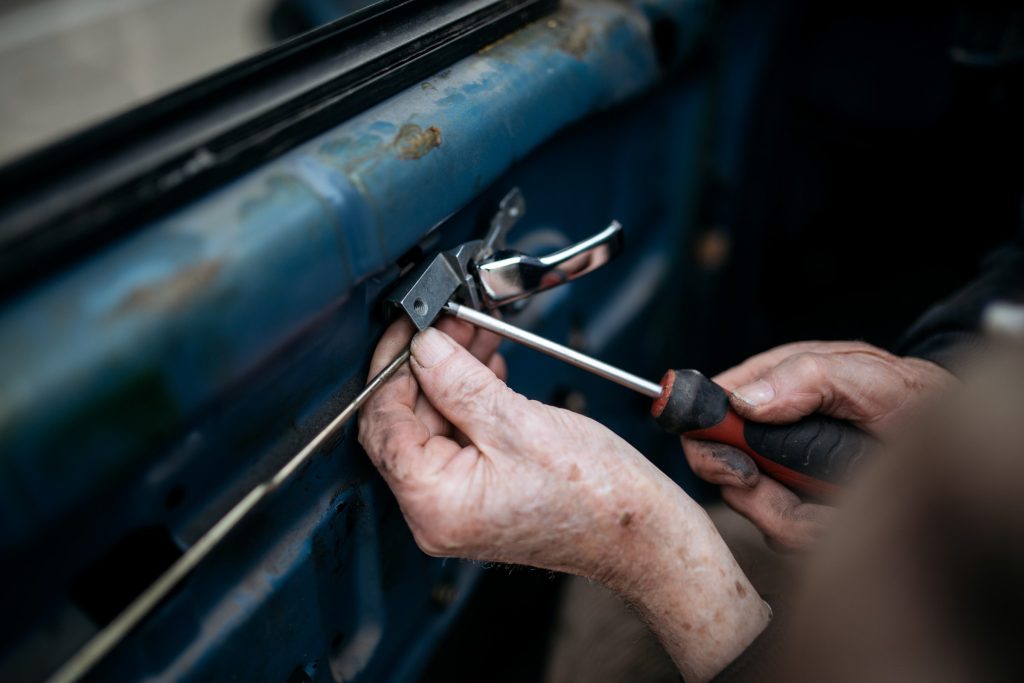 Handen die met een schroevendraaier een deurslot afstellen