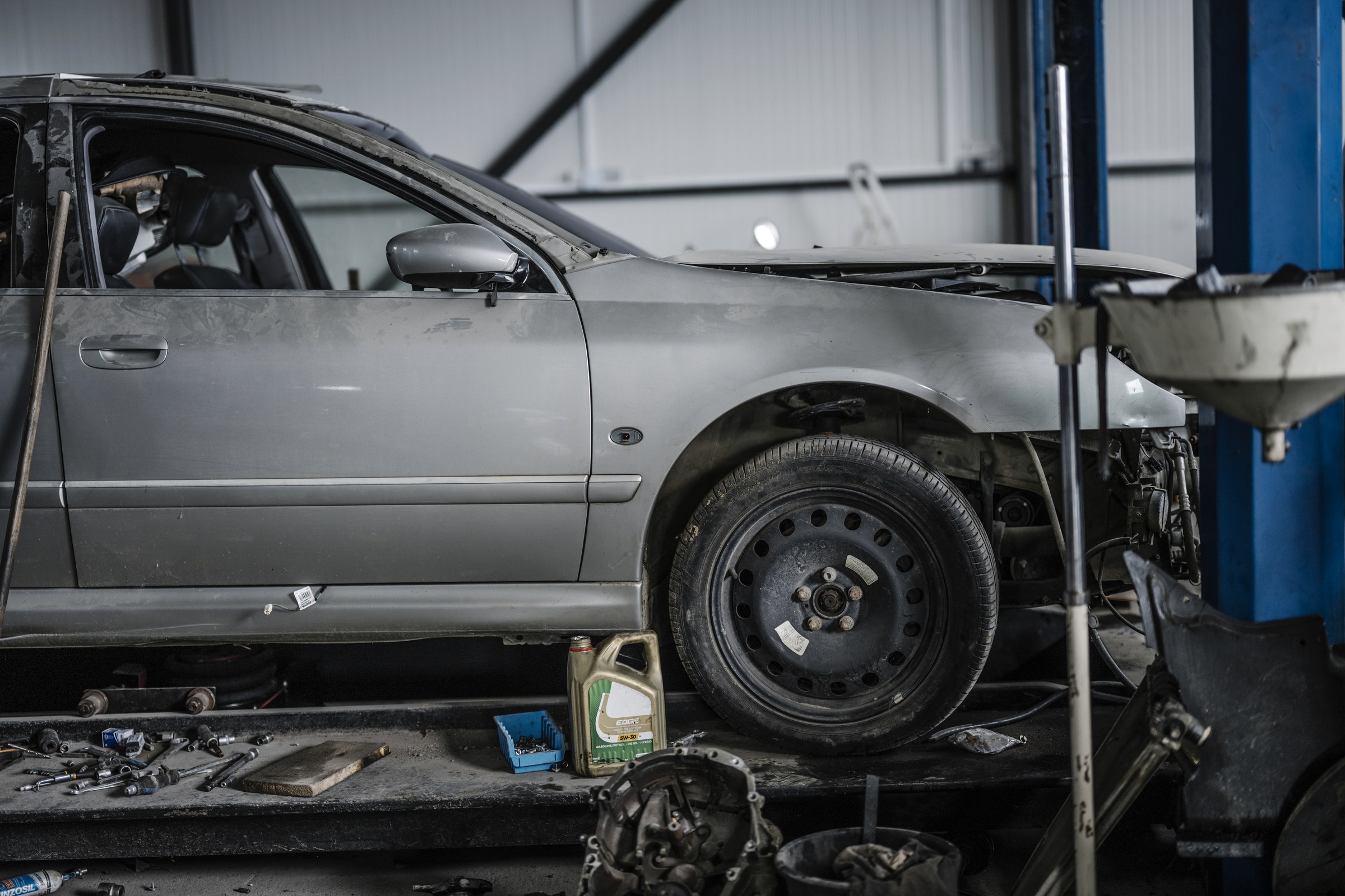 Auto op de brug in de werkplaats, met gereedschap op de vloer